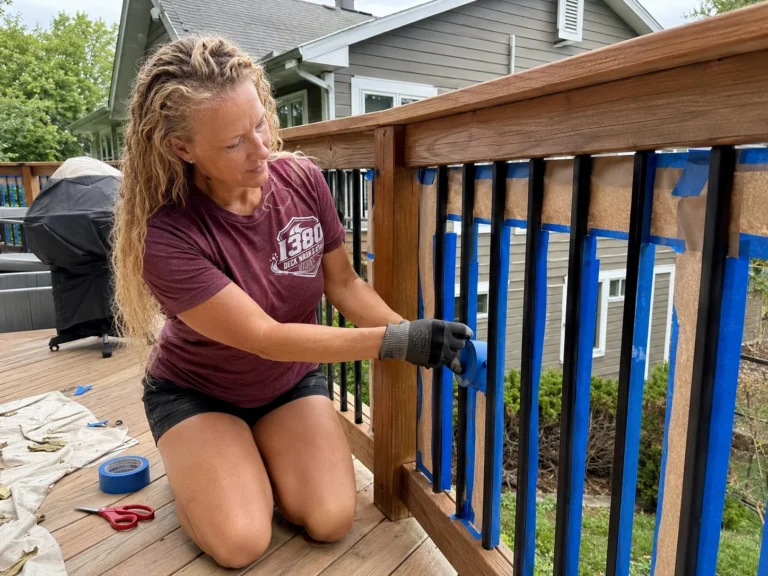 Worker masking deck balusters before staining the railing
