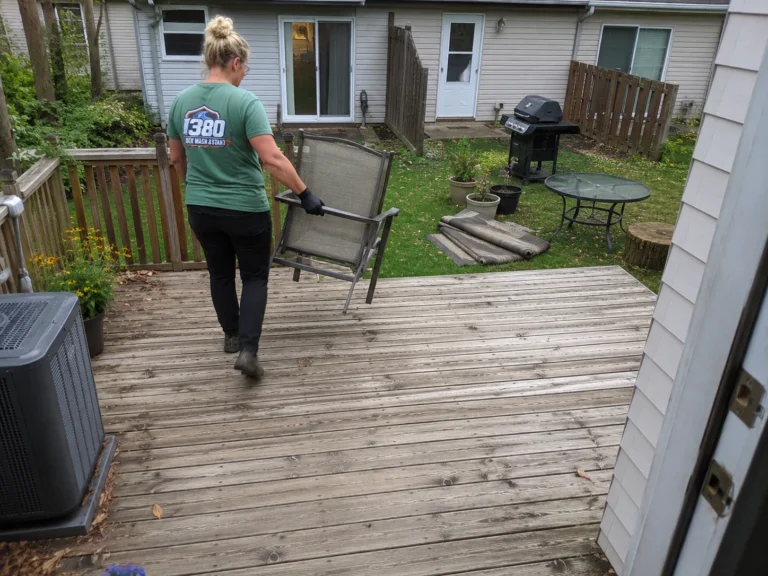 Worker using a blower to remove debris from weathered deck boards